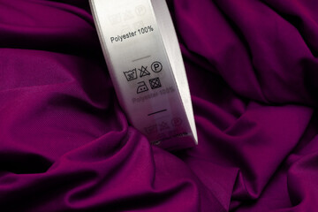 Polyester fabric Clothing label with laundry instructions. label with care symbols and material content on polyester shirt, close up. Clothing label with care symbols and material content