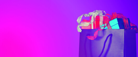Group of gift boxes in black shopping bag on web banner gradirnt futuristic color background,have space for idea.