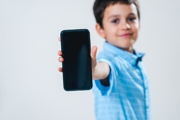 A schoolboy in a shirt with a bow tie demonstrates a smartphone screen. Focus on the smartphone. Conceptual. Copy space.