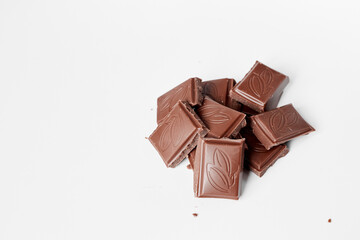 Milk chocolate pieces isolated on white background from top view, close up a chocolate bar isolated on white background