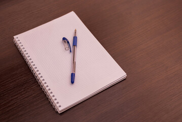 Blank notepad with pen on top of wooden office table. Top view with copy space, flat lay