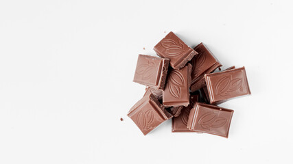Milk chocolate pieces isolated on white background from top view, close up a chocolate bar isolated on white background
