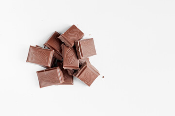 Milk chocolate pieces isolated on white background from top view, close up a chocolate bar isolated on white background