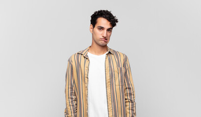 young handsome man feeling clueless, confused and uncertain about which option to pick, trying to...