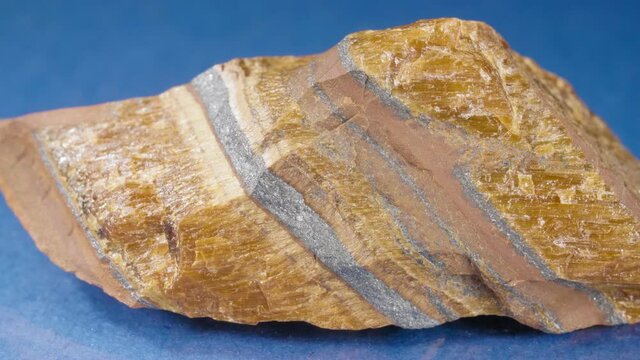Mineral tiger eye on a blue background. Decorative and ornamental stone.