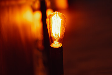 Filament lamp lit with black background, emitting light and brightening the environment