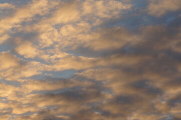 Clouds in the blue sky in the evening, during autumn, warm colours - background.