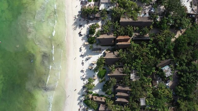 Vista a&eacute;rea cenital sobre Tulum Beach, en Tulum, Quintana Roo, con las olas rompiendo sobre la arena y el detalle de la tradicional arquitectura de la regi&oacute;n.