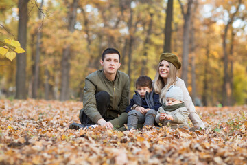 happy family Mom, dad and two little kids playing in autumn outdoor.