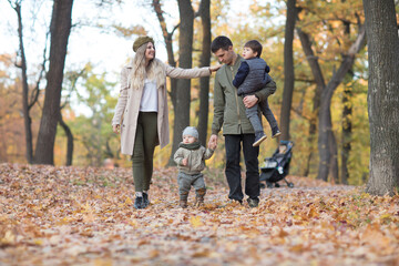 Naklejka na ściany i meble happy family Mom, dad and two little kids playing in autumn outdoor.