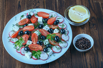 a plate of salad with red tomato, black pepper and cheese on a wooden table