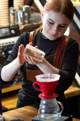Barista barista pouring manual drip brewer to make coffee. Girl pouring water on coffee ground with filter. Alternative pure over method.