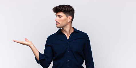 young handsome man feeling happy and smiling casually, looking to an object or concept held on the...