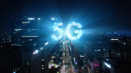 5G technology concept in the city of the future. Beautiful aerial panorama of modern skyscrapers, streets and traffic all in glittering lights on the night. 