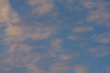 Clouds in the blue sky in the evening, during autumn, warm colours - background.