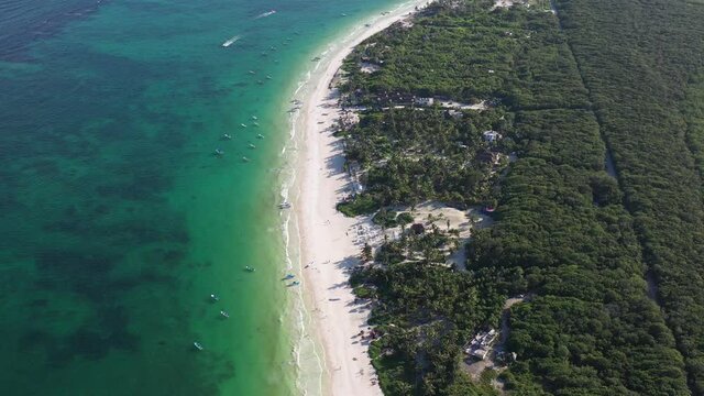 Detalle a&eacute;reo sobre la Playa de Tulum, algunas barcas en el mar azul turquesa y personas caminando sobre la playa.