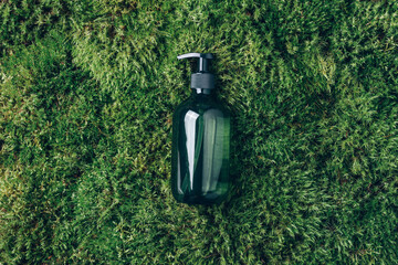 Unlabelled cosmetic bottle on green moss background. Biophilic design. Skin care, organic body...