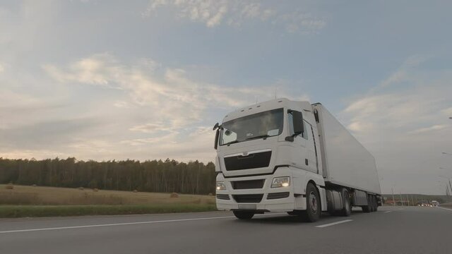 White truck with trailer driving on road, cargo transportation.
