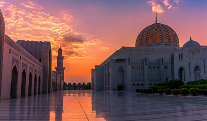 A vibrant sunset illuminates a mosque at sunset in Muscat, Oman in late summer