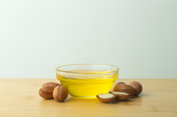 Argan oil background. Argan nuts  and oil on a wooden table on a empty white background. Copy space