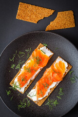 rye crispbread with cream cheese and salmon on black background
