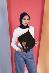 Muslim girl models pose like famous models. The woman wearing hijab wears casual clothes while...