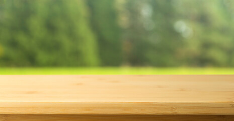 Nature table background.  Empty wooden table on the blurred background of summer sunny nature, grass and forest.