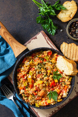 Turkish cuisine. Menemen Scrambled eggs in a cast iron frying pan on a stone countertop. Top view flat lay background. Copy space.