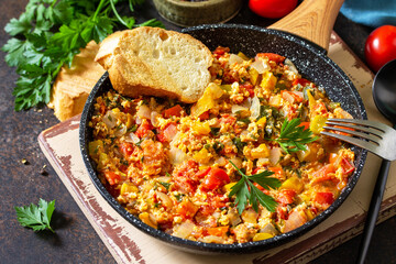 Turkish cuisine. Menemen Scrambled eggs in a cast iron frying pan on a stone countertop.