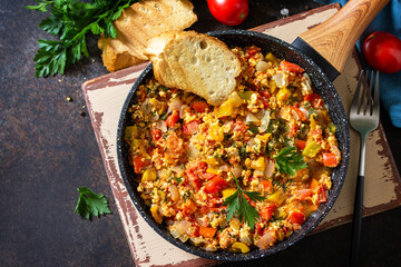 Turkish cuisine. Menemen Scrambled eggs in a cast iron frying pan on a stone countertop. Top view flat lay background. Copy space.