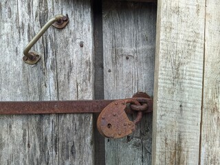 powerful steel and rusty closed padlock on a wooden barn door