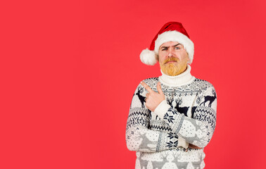 Fototapeta na wymiar serious man santa hat. bearded hipster dyed hair red background. new year party is here. copy space. christmas shopping time. mature male knitted xmas sweater. brutal man hate winter holidays