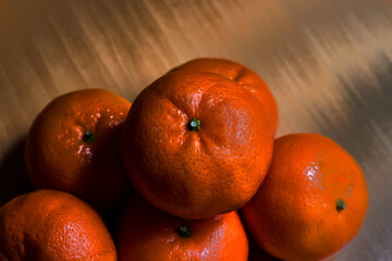 Closeup of several ripe tangerines, one on top of the other, on a wooden table