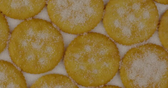 Rotate shot of spread round cracker on white background with sweet sugar falling down