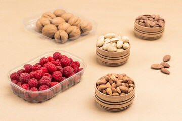 Raspberries and walnuts in plastic containers. Nuts in wooden boxes.