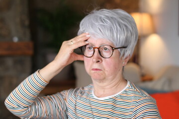 Stressed senior woman touching forehead