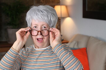 Shocked senior woman holding eyeglasses