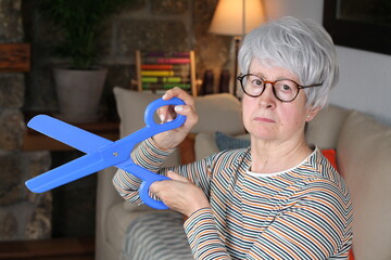 Senior woman holding large plastic scissors 