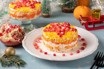 Festive New Year's salad with chicken, eggs, carrots and corn, decorated with a star of pomegranate seeds on light blue background, Horizontal format