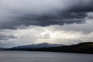 Fototapeta premium View of Scenic Lake and Mountains on a Moody Overcast Day in Canadian Nature. Taken near the Klondike Highway, Yukon, Canada.