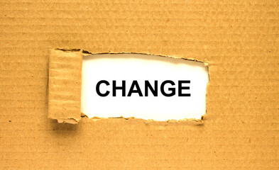 The word Change appearing behind torn brown paper