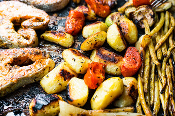 Baked vegetables, potatoes, asparagus, beans, tomatoes, salmon steaks
