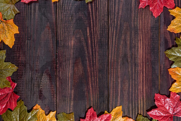 dark wooden background with maple leaves along the edges. space for notes