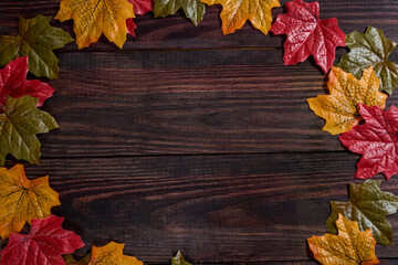 dark wooden background with maple leaves along the edges. space for notes