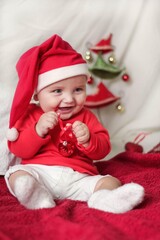 A beautiful little child is celebrating Christmas. New year holiday. Baby in a Christmas costume is happy sitting on the floor