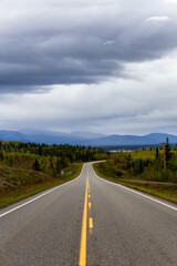 View of Scenic Road surrounded by Mountains and Trees on a Fall Day in Canadian Nature. Klondike Highway, Yukon, Canada.
