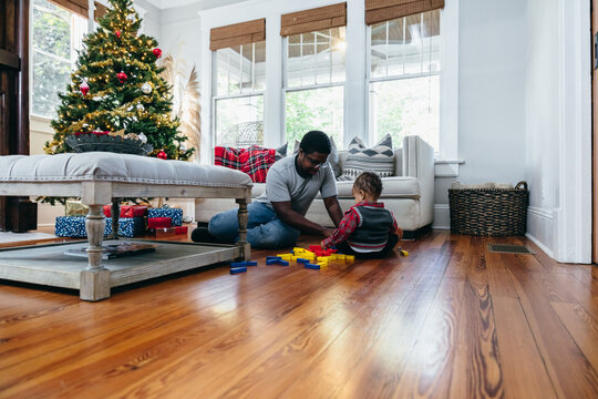 Black father and son play in living room during Christmas holidays