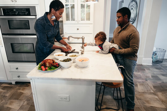 Young Black family prepares food in kitchen for holiday gathering
