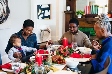 Family praying together before Kwanzaa holiday meal