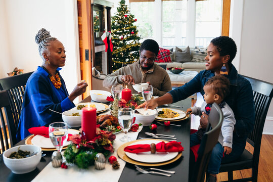 Multigenerational black family eating Christmas dinner together at dining toom table